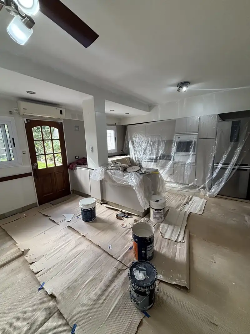 Cocina con muebles cubiertos con nylon, pisos protegidos y latas de pintura, antes de pintar