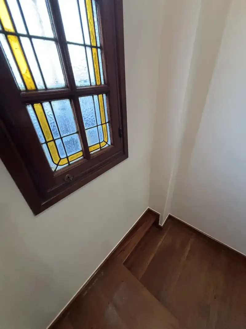 Descanso de escalera con paredes blancas recién pintadas y ventana con vitral