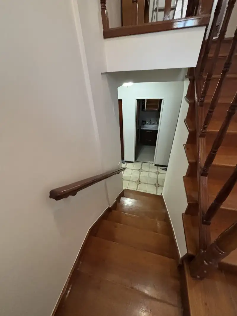 Escalera de madera y palier con paredes blancas recién pintadas