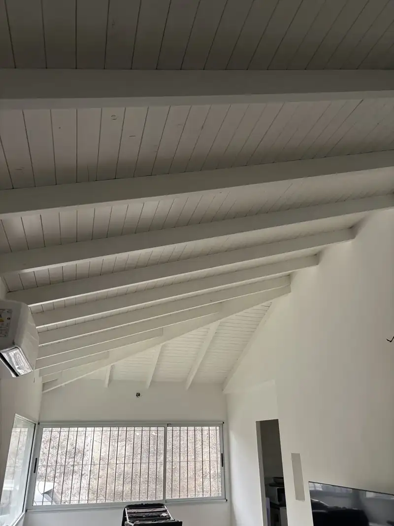 Living con cielorraso de machimbre pintado de blanco y vigas a la vista