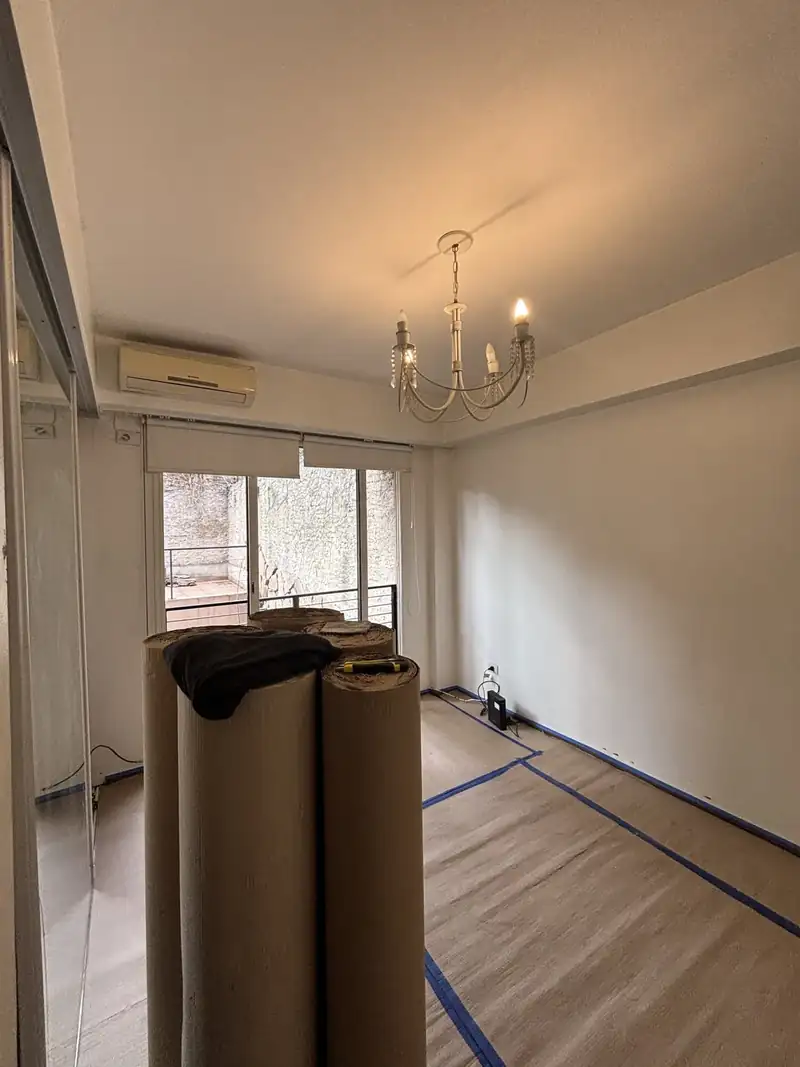 Living con el piso protegido con cartón y cinta, listo para pintar