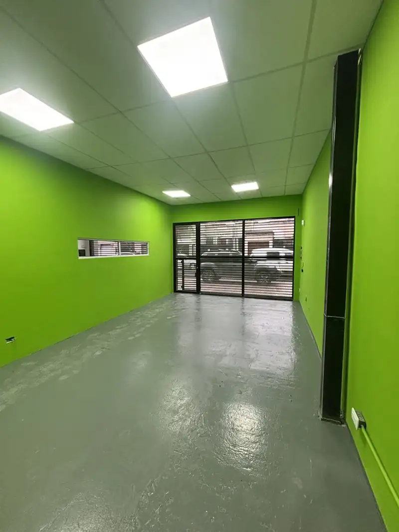Local comercial terminado con tabiques pintados de verde, cielorraso desmontable con paneles LED y piso gris