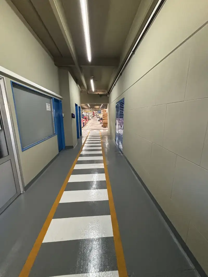 Pasillo de planta industrial con demarcación nueva de franjas blancas y grises y bordes amarillos