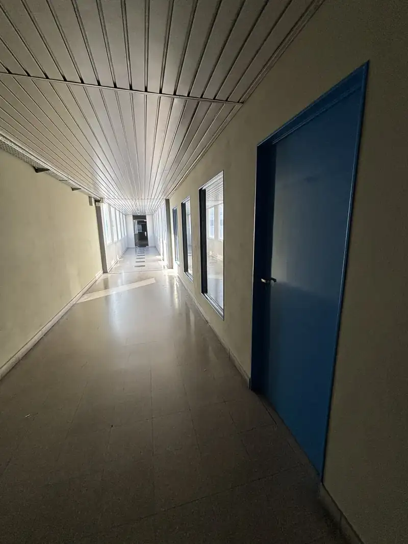 Pasillo de oficinas con paredes claras y puertas azules recién pintadas