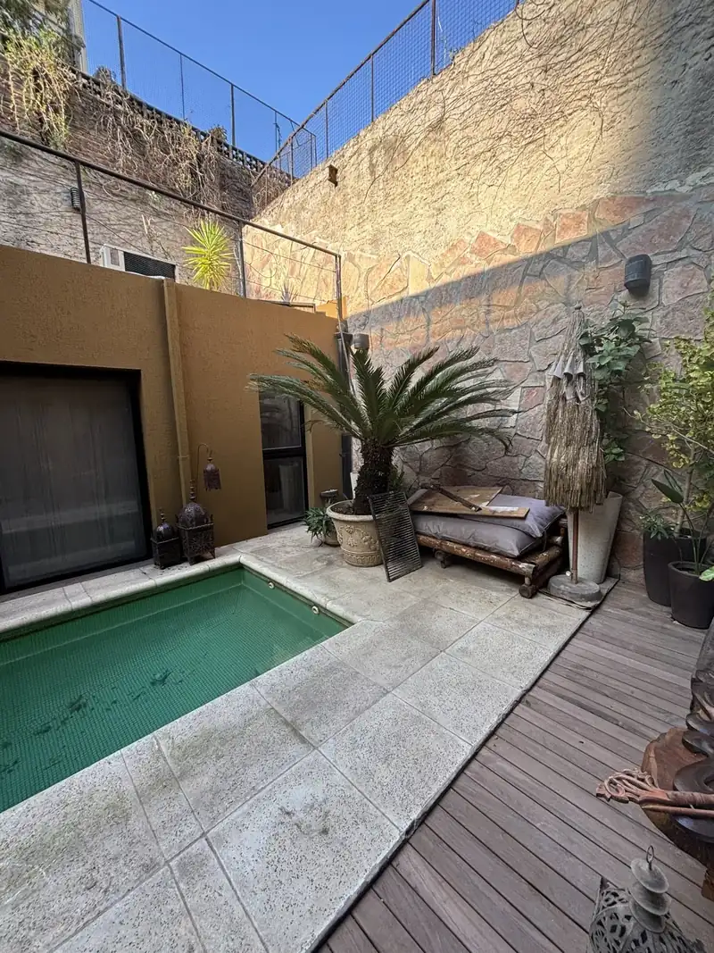 Patio interno con pileta y muro con revestimiento texturado color ocre, pintado a nuevo